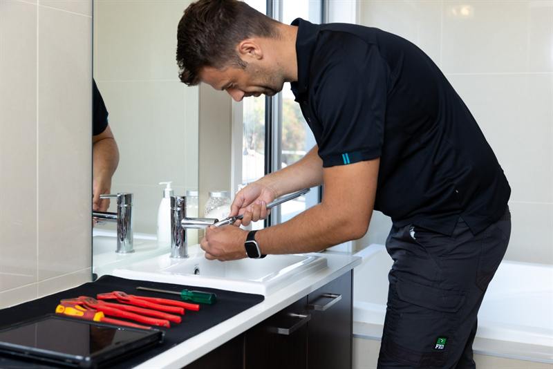 Plumber fixing a leaking kitchen tap